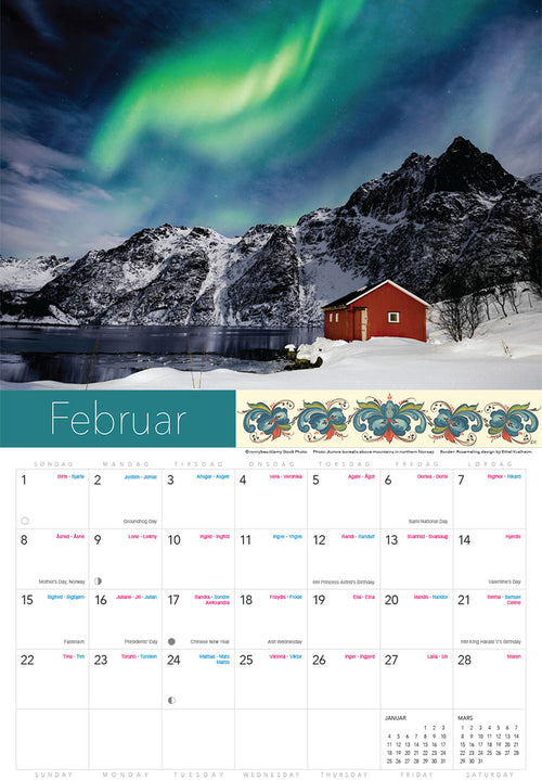 A red cabin rests by a snowy lake with mountains behind and vivid green northern lights overhead. The Splendor of Norway Calendar 2026 showcases this scene for February.