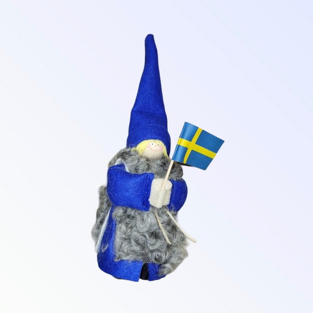 The Figurine: Swedish Boy with Flag, featuring a long blue hat and gray beard, proudly holds a small Swedish flag. Made in Sweden using authentic techniques, this handcrafted piece captures the charm of traditional craftsmanship.