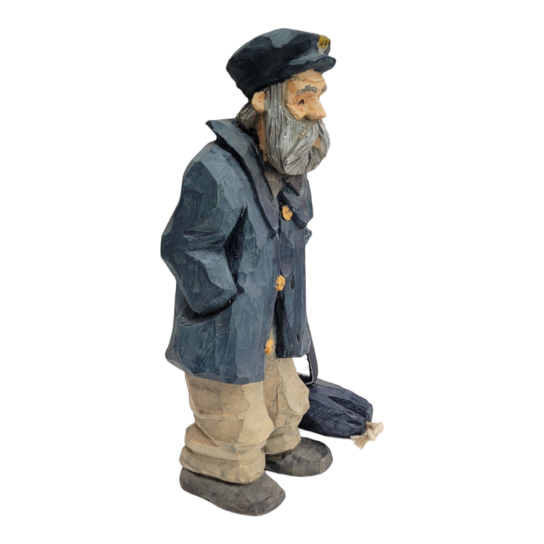 The "Home Port" figurine by Bill Erickson features an intricately hand-carved depiction of an old sailor with a white beard, dressed in a blue coat and cap, carrying a bag.