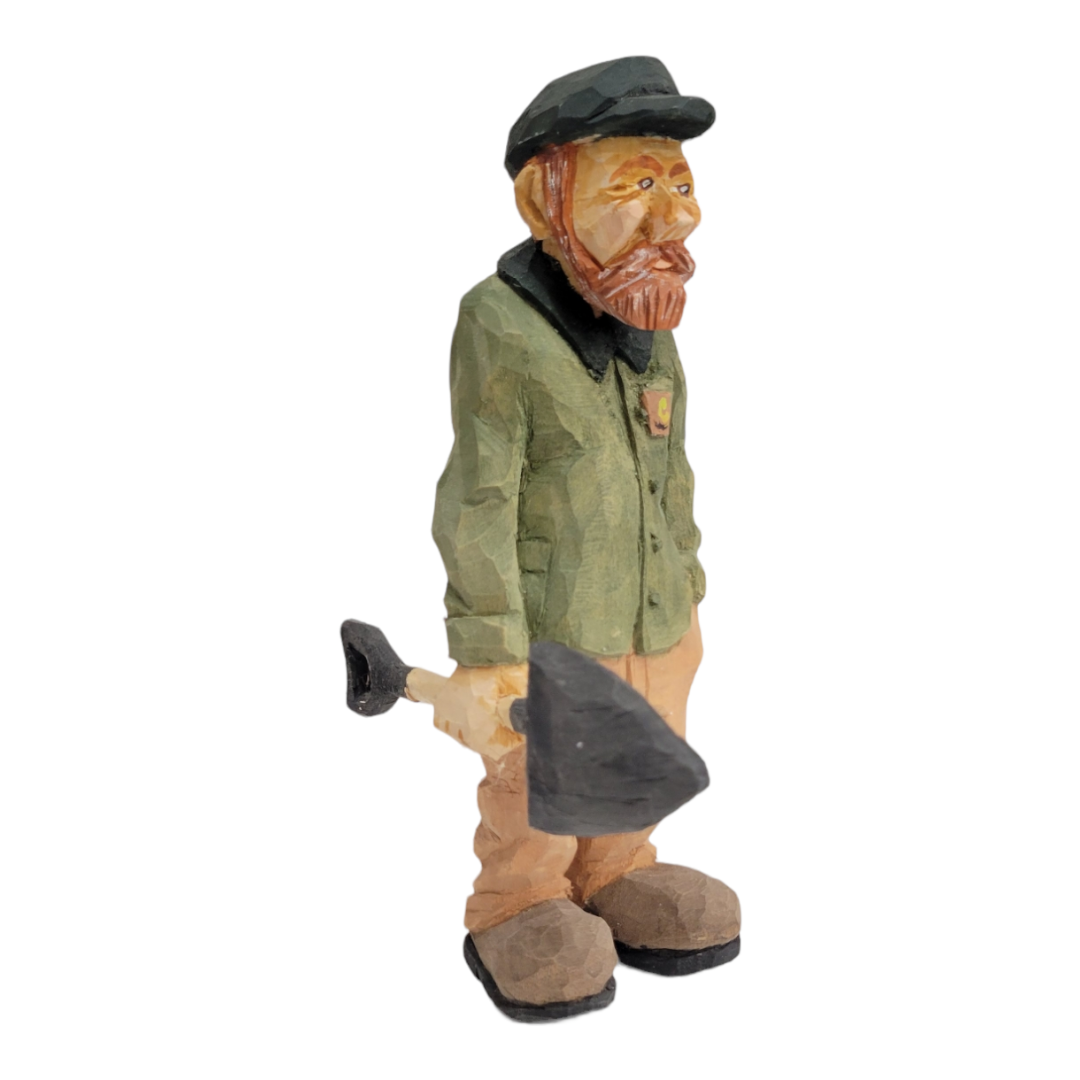 The "Johannes with Shovel" figurine, a copy by Bill Erickson, features a wooden carving of a bearded man in a green jacket and cap, holding a shovel. This piece exemplifies intricate craftsmanship and timeless charm.