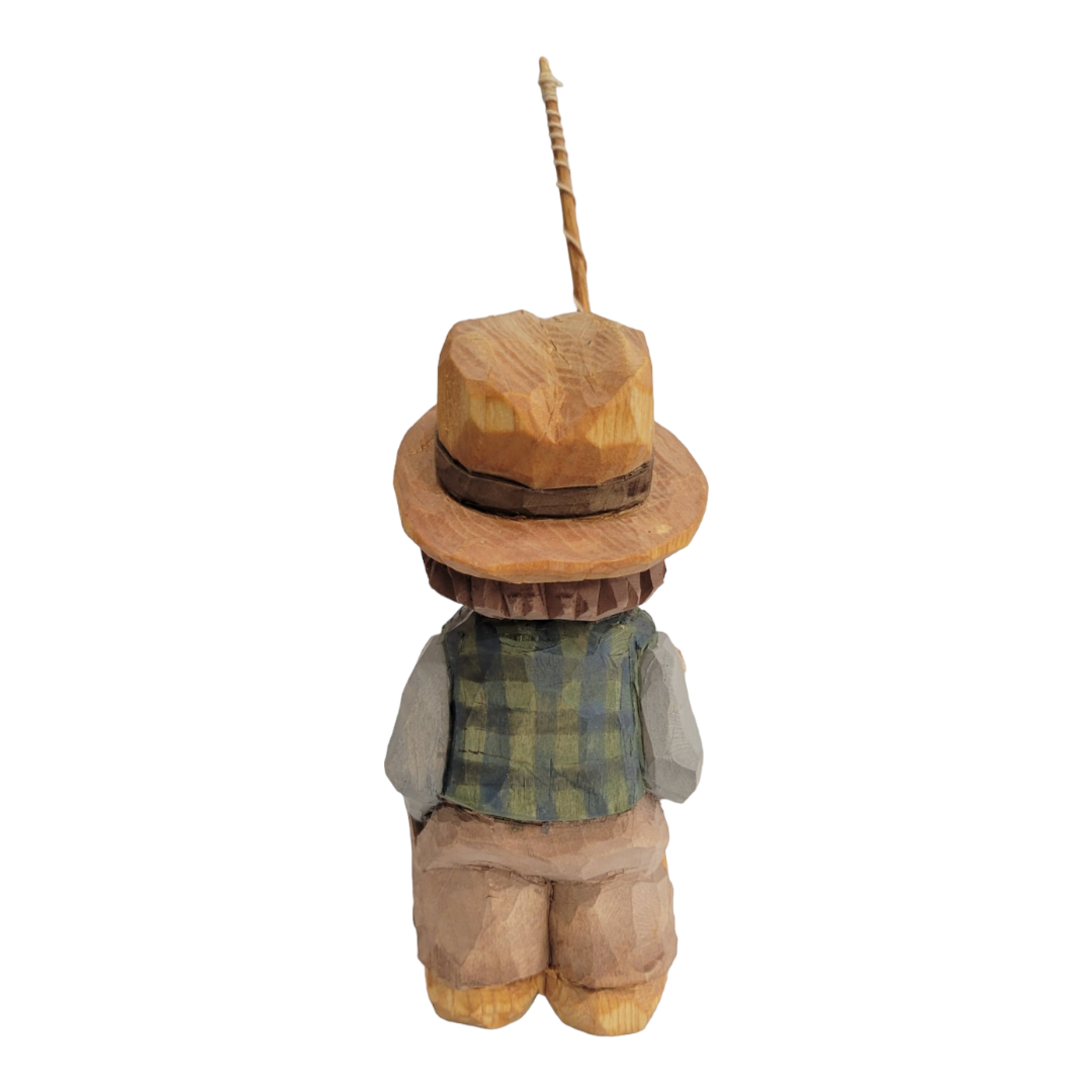 This hand-painted figurine, "Fisherman" by Bill Erickson, depicts a wood-carved person wearing a hat and plaid vest, facing away with a fishing rod over the shoulder. It beautifully captures the essence of serenity reminiscent of Erickson's iconic style.