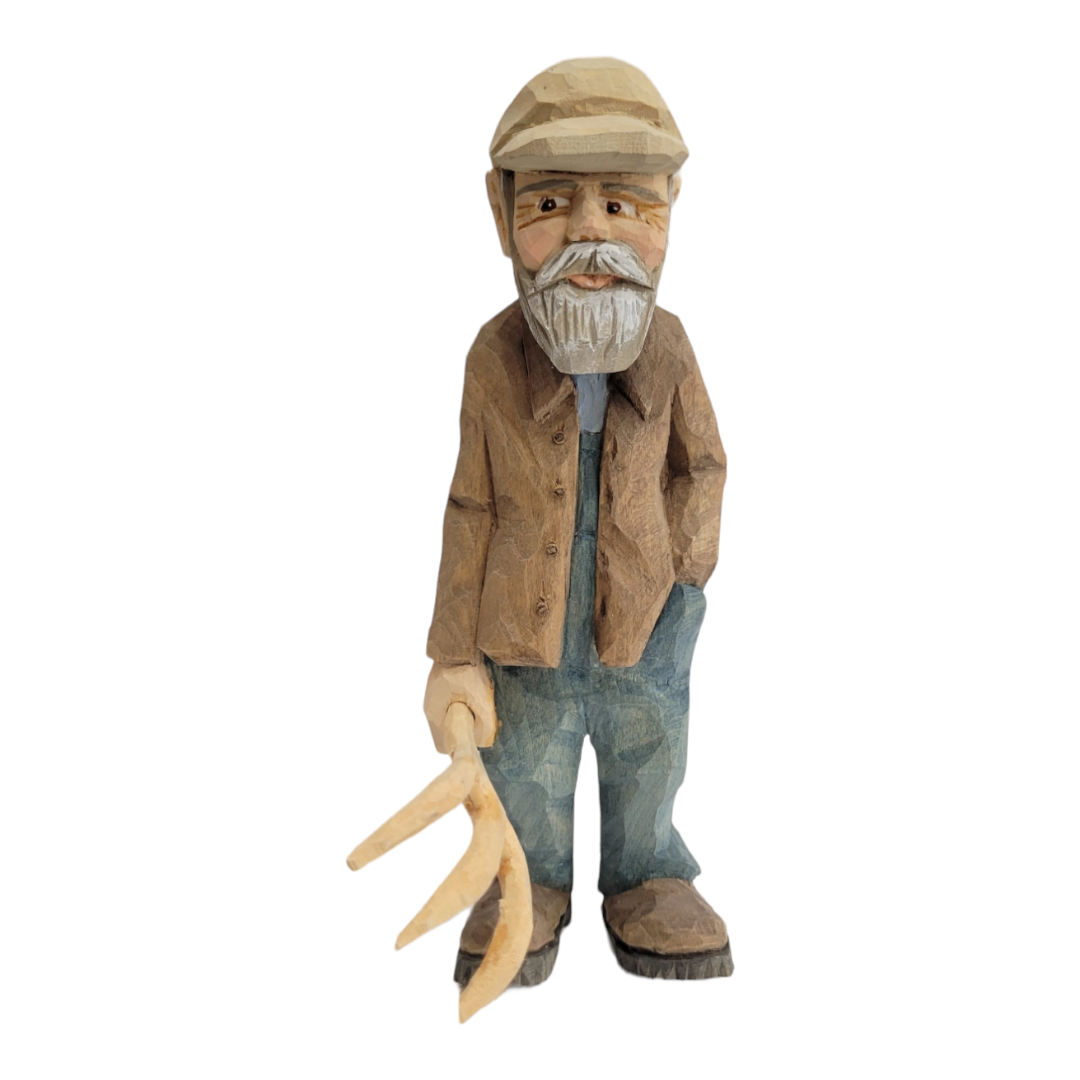 The hand-carved figurine, "Johannes" by Bill Erickson, portrays a bearded man in a brown jacket and cap, skillfully crafted while holding a pitchfork with impressive detail.