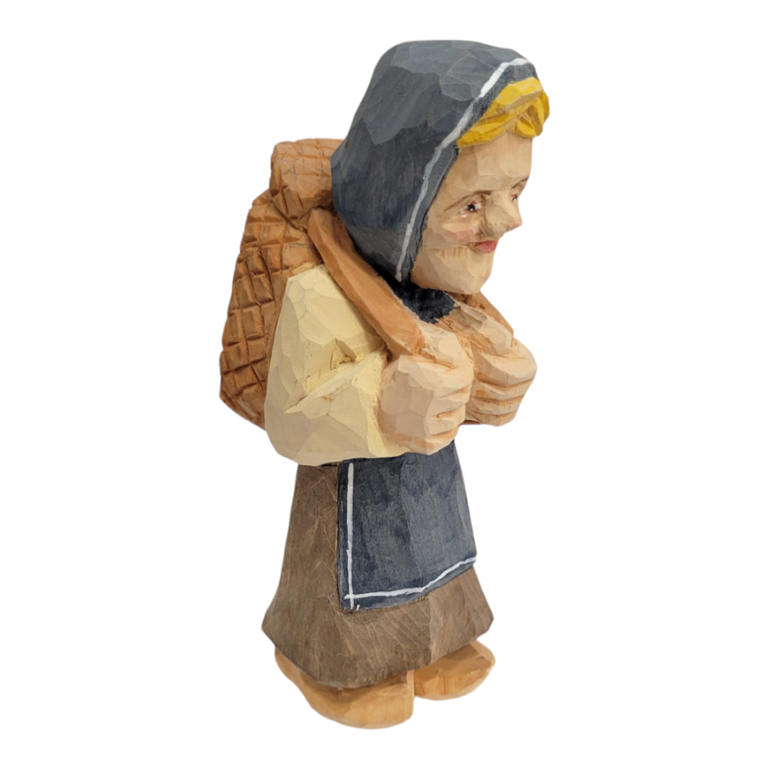 Wood carved "Katrina" figurine by Bill Erickson, depicting a person in a hooded cloak carrying a basket. This hand-painted piece features intricate details, showcasing Bill Erickson's timeless craftsmanship.