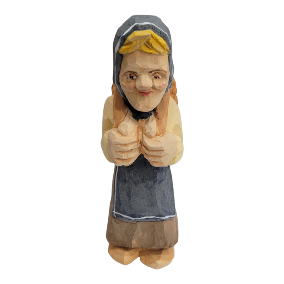 Hand-painted and carved wooden figurine titled "Katrina" by Bill Erickson, featuring a person in a hood and apron with hands folded in front, standing upright.