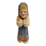 Hand-painted and carved wooden figurine titled "Katrina" by Bill Erickson, featuring a person in a hood and apron with hands folded in front, standing upright.