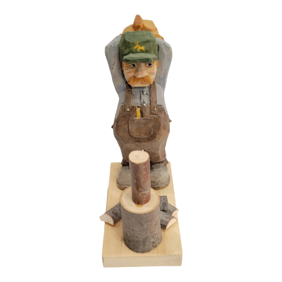 The product is a hand-painted, wood-carved figure titled "Woodchopper" by Bill Erickson. It depicts a woodchopper in overalls and cap, leaning over with hands on their back, standing on a wooden base with a cut log in front.