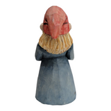 A hand-carved figurine portrays a woman holding a flower.
