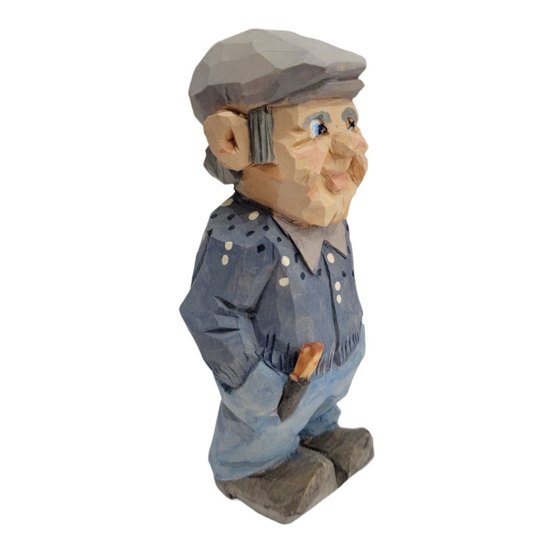 The "Lars" figurine by Bill Erickson is a 6-inch wood carving depicting a man with a cap, wearing a blue shirt and jeans, standing with his hands in his pockets.