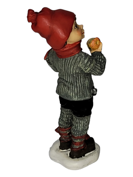 The Figurine: Apple Boy Large captures the enchanting style reminiscent of Carl Larsson, showcasing a child in winter attire with a red hat and scarf. Gracefully poised on a white base, the figure holds an apple, exuding a hint of Norwegian design elegance.