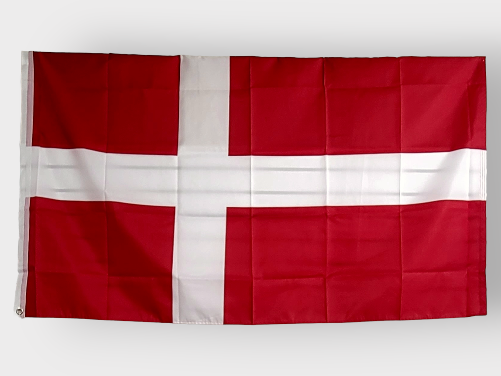 The image showcases the Denmark Polyester Flag (3'x5'), which displays a white Scandinavian cross on a red background. Made from polyester, this flag is UV-protected and weather-resistant, ensuring that it maintains its vibrant colors in all conditions.