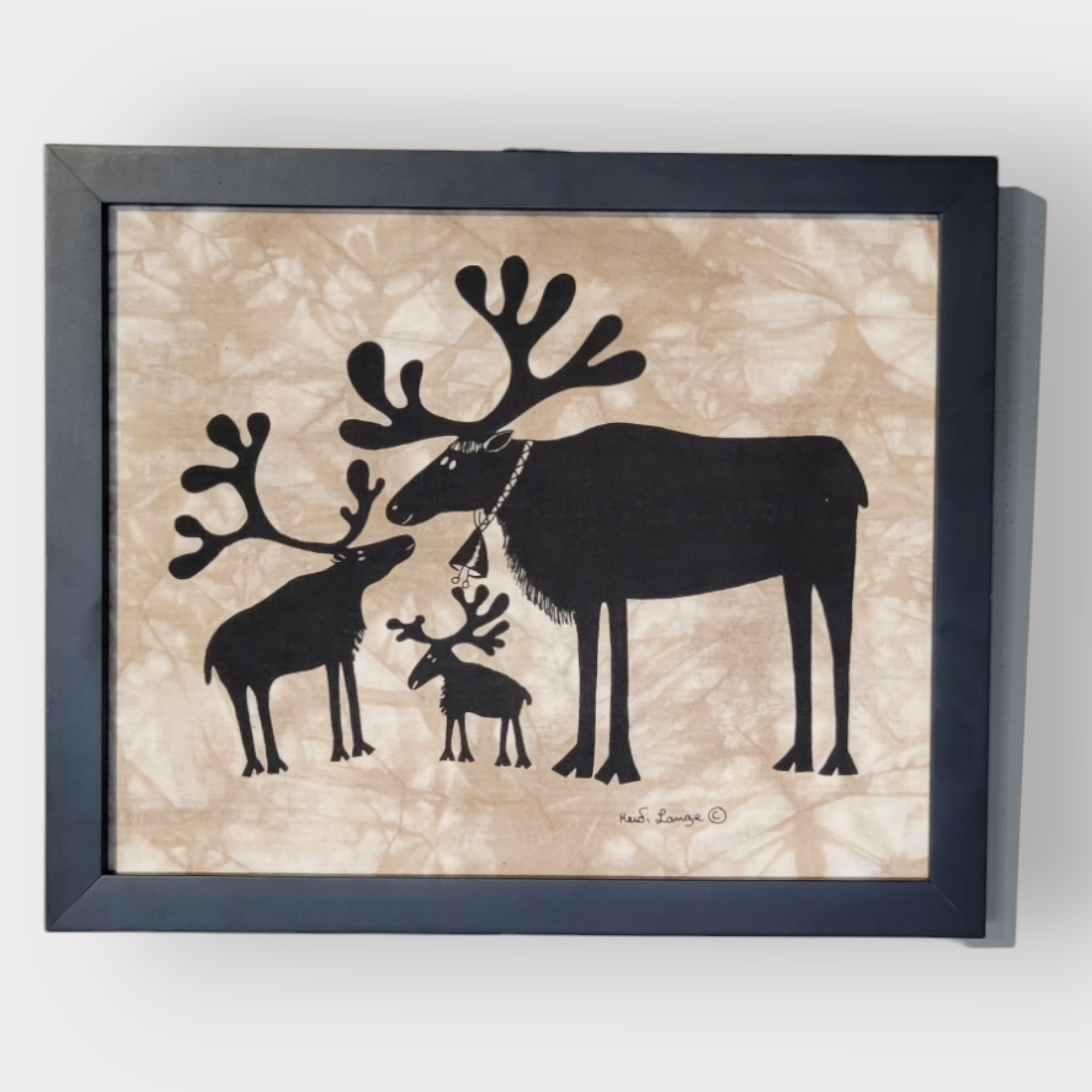 This 14" by 11" framed artwork, titled "Reindeer Family," showcases three majestic black silhouettes of moose with impressive antlers set against a beige background, crafted in the distinctive style of Heidi Lange.