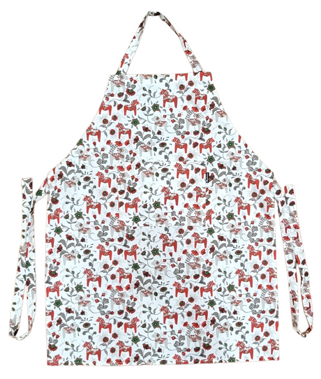 The Leksand Mini Swedish Dala Horse Apron showcases a charming pattern of red horses and green leaves on white, capturing the essence of Arvidssons Textile design. Available in 4 color options.