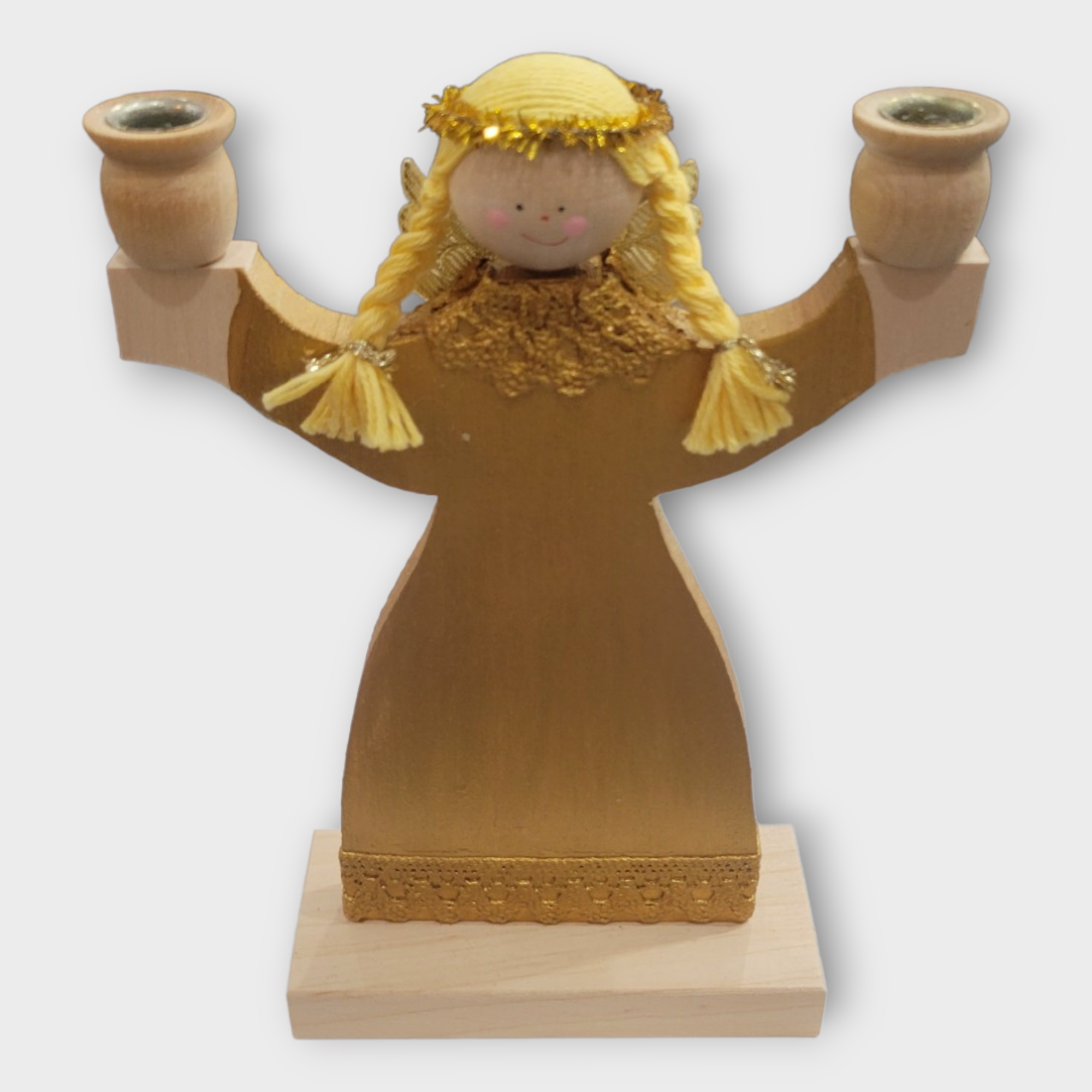 This exquisite piece of home décor, known as the Candle Holder: Angel, Two-Candle Holder, is a refined wooden figurine ideal for gifting to anyone who loves angels. It features blonde braided hair and wears gold attire, gracefully holding a candleholder in each hand while standing on a square base.