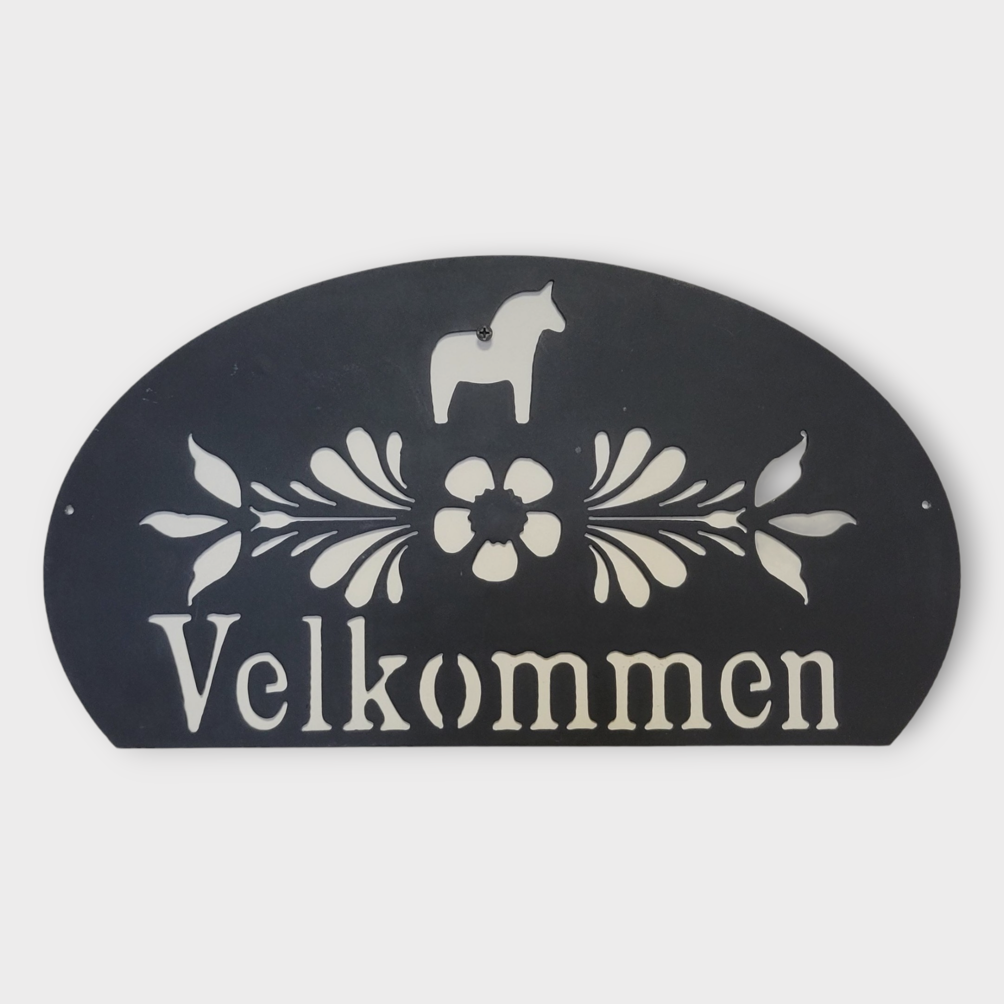 The Velkommen wall decor is a black and white metal welcome sign featuring a horse silhouette adorned with Swedish floral designs.