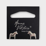 Silver Dala earrings shaped like horses, presented on a black card labeled Anna Viktoria, Design of Sweden, beautifully highlight the authentic charm of Scandinavian jewelry.