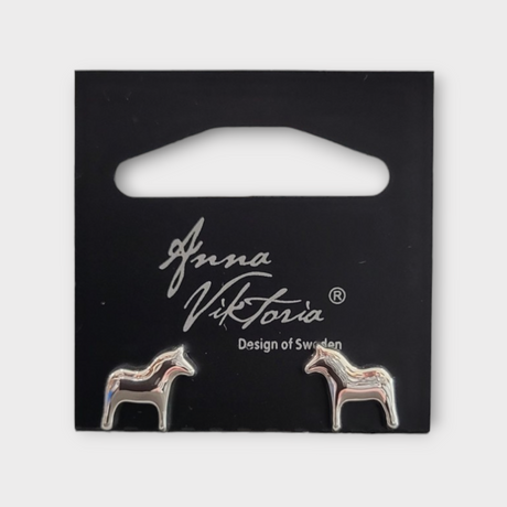 Silver Dala earrings shaped like horses, presented on a black card labeled Anna Viktoria, Design of Sweden, beautifully highlight the authentic charm of Scandinavian jewelry.