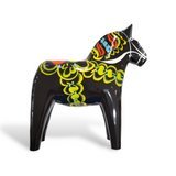 The Dala Horse: Black is a hand-carved figurine featuring vibrant patterns in yellow, blue, and red on its body and mane, representing an iconic piece of Swedish traditional handcraft.