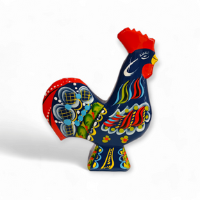 The Dala Rooster: Blue, a wooden figurine that evokes the charm of traditional Swedish handcraft, features detailed designs and a striking blue crest. It stands elegantly in profile against a simple white background, embodying the timeless appeal of classic Dala roosters.
