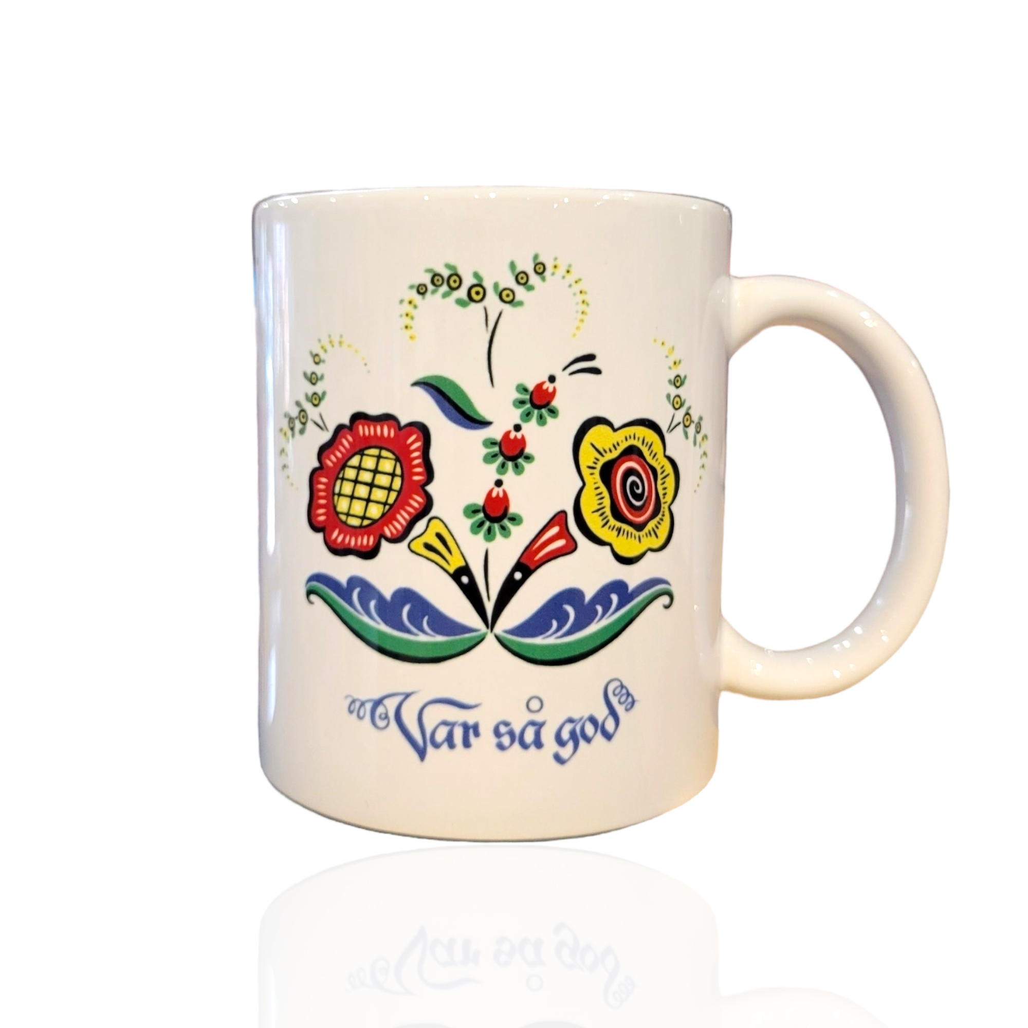 Enjoy your favorite drink in the Var så god Mug – Swedish Floral Design (11oz), a white ceramic mug featuring a colorful Scandinavian-style floral pattern and the phrase Var så god in blue script, honoring Swedish hospitality.