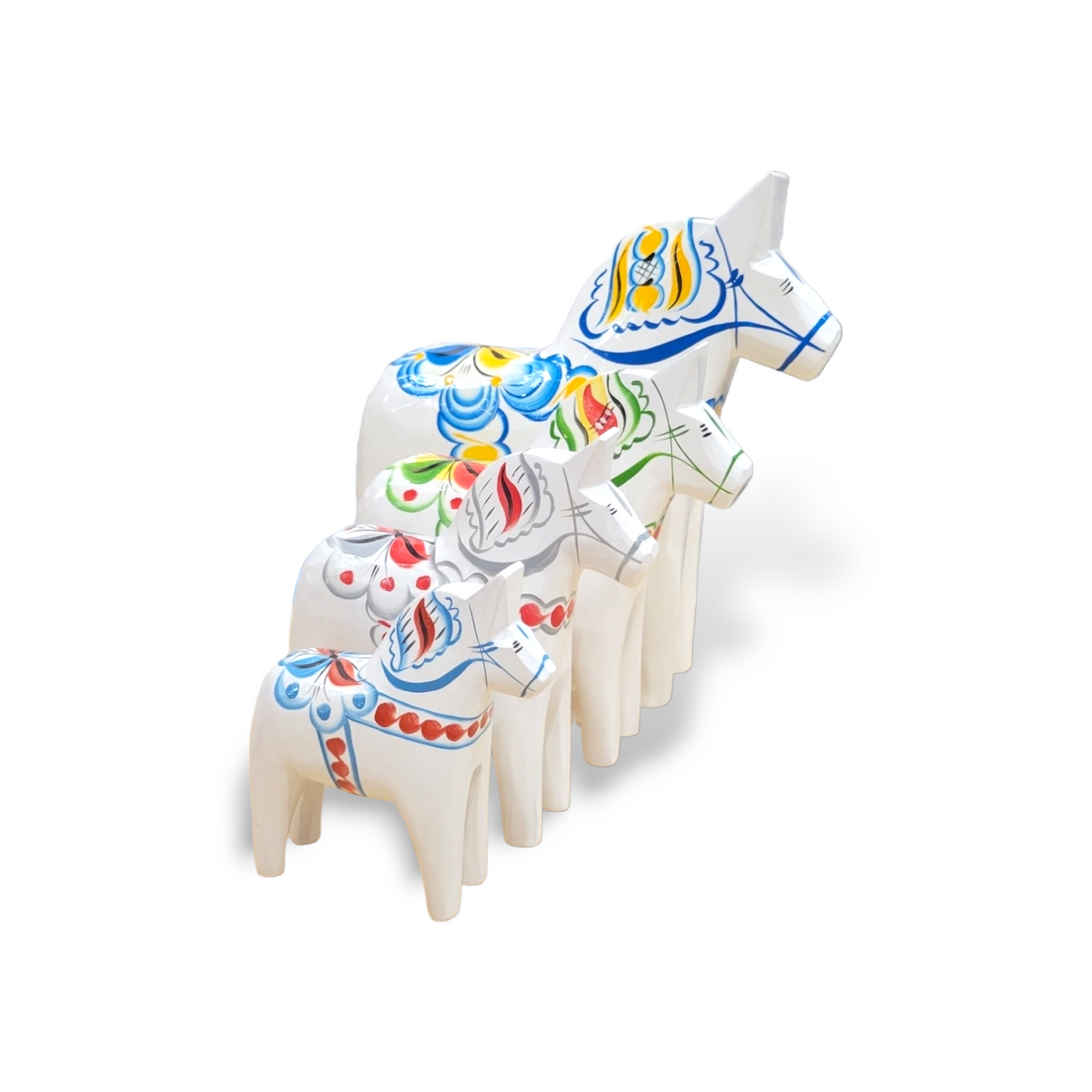 A set of five hand-carved Dala Horses, named White Base with Multi-Color Trim Swedish Dala Horse, arranged from smallest to largest, showcases their colorful painted designs.