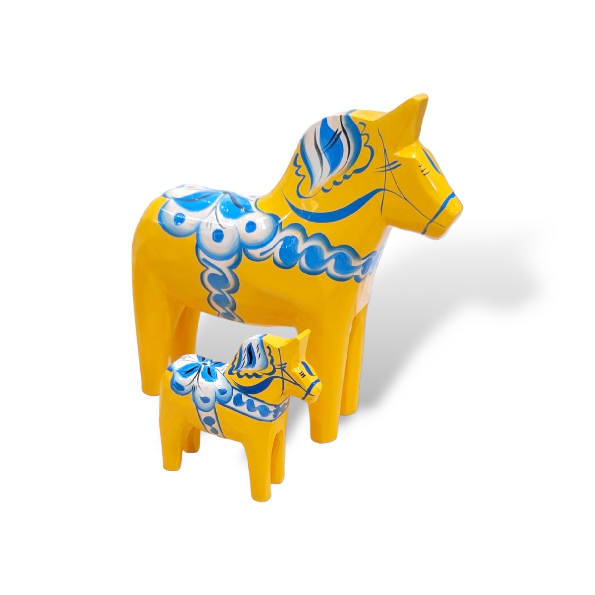A large and a small handcrafted Dala Horse from the Swedish Flag Series, painted yellow with blue kurbits designs, stand on a white background with visible shadows.