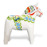 The Dala Horse: White Base with Multi-Color Trim Swedish Dala Horse is a white ceramic figurine, featuring vibrant patterns in blue, green, and red on a pristine white background.