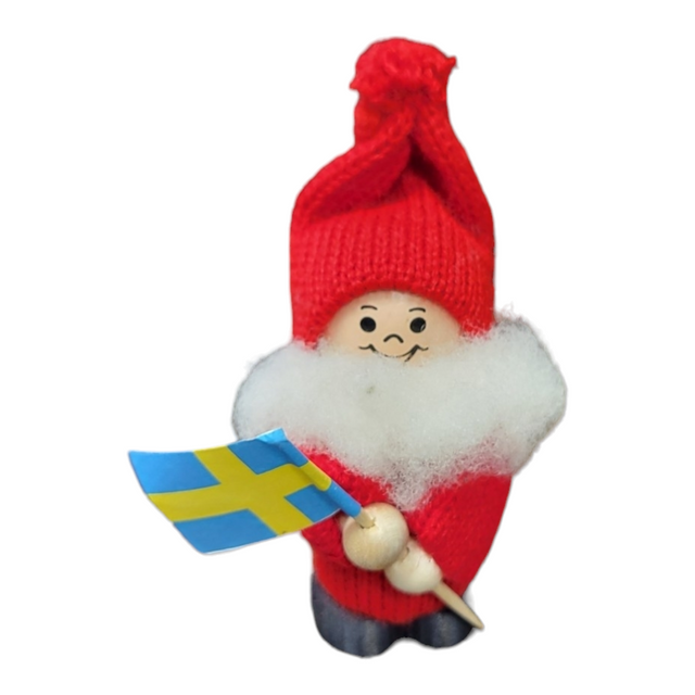 The 3 tall handcrafted Santa figurine, Santa with Swedish Flag - Boy or Girl, features a red hat and outfit, a white fluffy beard, and proudly holds a Swedish flag against a plain background, showcasing Swedish charm.