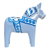 Against a white background, an intricately hand-carved and painted light blue ceramic Dala horse figurine captures the essence of Swedish traditional craftsmanship with its dark blue and white patterns.