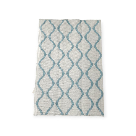 The Rug: Wave Blue is a white kitchen towel that boasts a blue wavy line pattern, ensuring both durability and longevity.