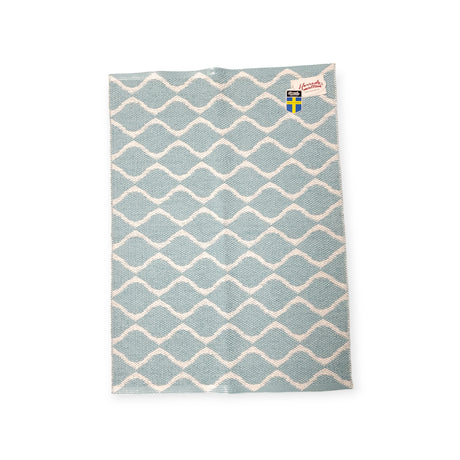 Swedish dishcloth featuring a blue and white wavy pattern, inspired by the long-lasting durability of the Rug: Wave Blue.
