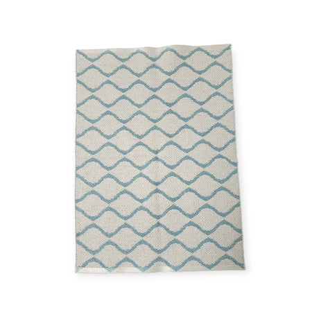 The Rug: Wave Blue features a geometric zigzag pattern in blue and white, crafted from durable Swedish vinyl, ensuring lasting appeal.