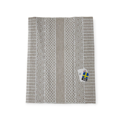 The Vinyl Rug: Horredsmattan - Alfie - Sand is a gray and white patterned Swedish rug with a woven design, lying flat with a tag attached, showcasing its environmentally friendly PVC composition.