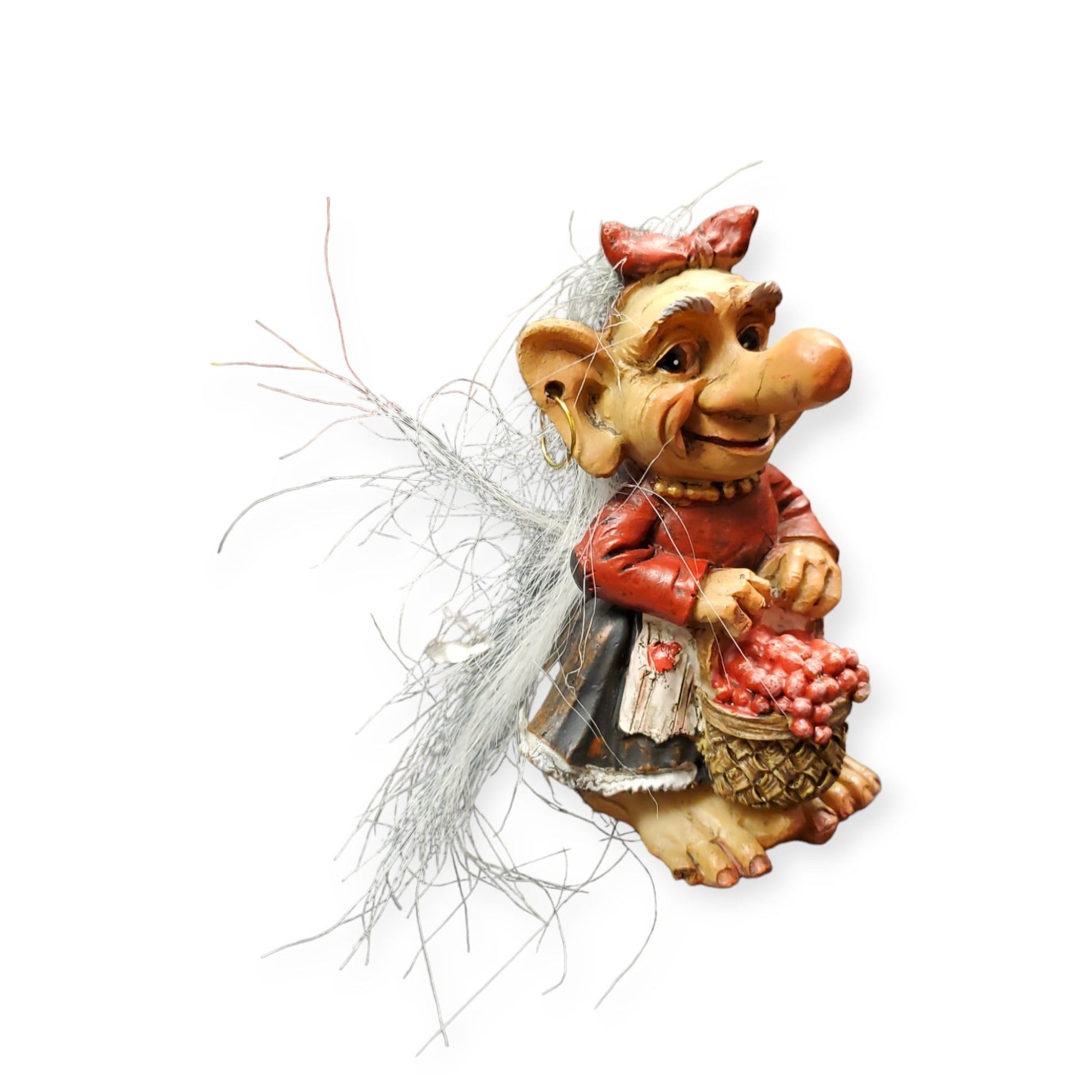 The "Troll: Troll w/Lingonberries" figurine features a cheerful character dressed in a vibrant red Norwegian outfit, carrying a basket of lingonberries. With long gray hair and a pointed nose, this figurine perfectly captures its whimsical charm.