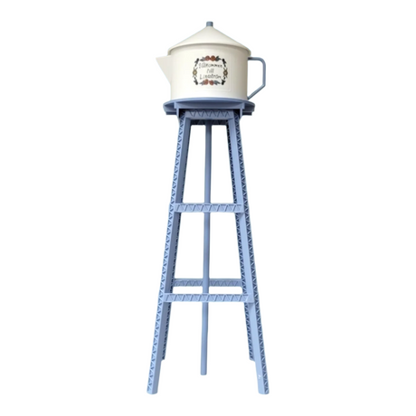 A tall blue metal stand supports a white teapot, resembling the Model Kit: Miniature Replica of the Lindström Coffee Pot Water Tower, set against a white background.
