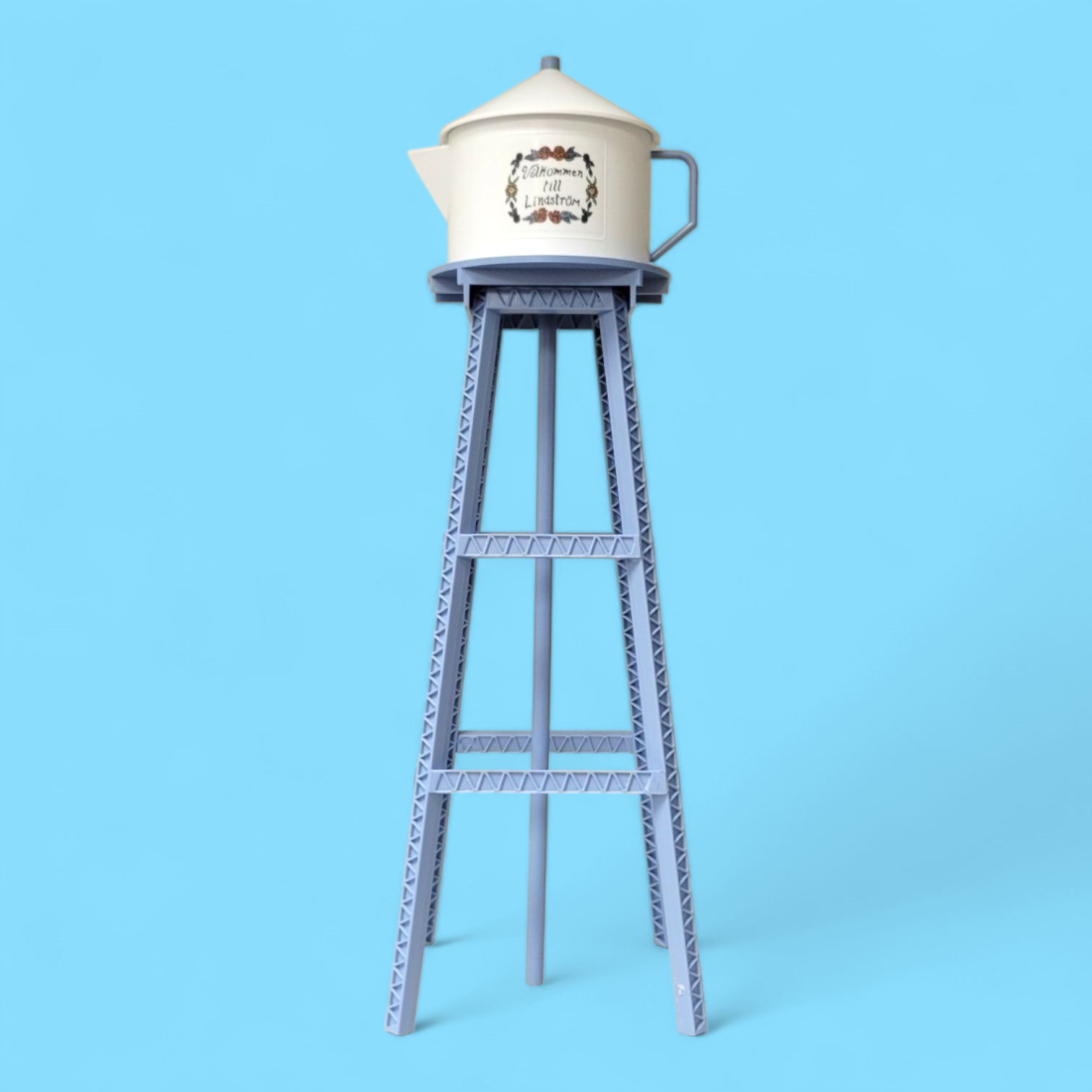 A Model Kit: Miniature Replica of the Lindström Coffee Pot Water Tower features floral designs and sits atop a tall blue metal structure, set against a solid light blue background.