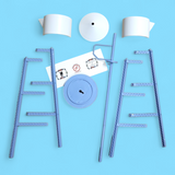 The Model Kit: Lindström Coffee Pot Water Tower – Miniature Replica features blue metal rods, circular disks, and white paper pieces arranged symmetrically on a light blue surface, evoking the iconic Minnesota landmark.