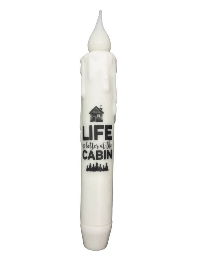 Experience the warmth and simplicity of cabin life with the Candle: Cabin Life 7" Tapered LED Light. With wax drips and a cozy cabin design, this battery-operated timer candle showcases the text "Life is better at the cabin," embodying charm in any space.