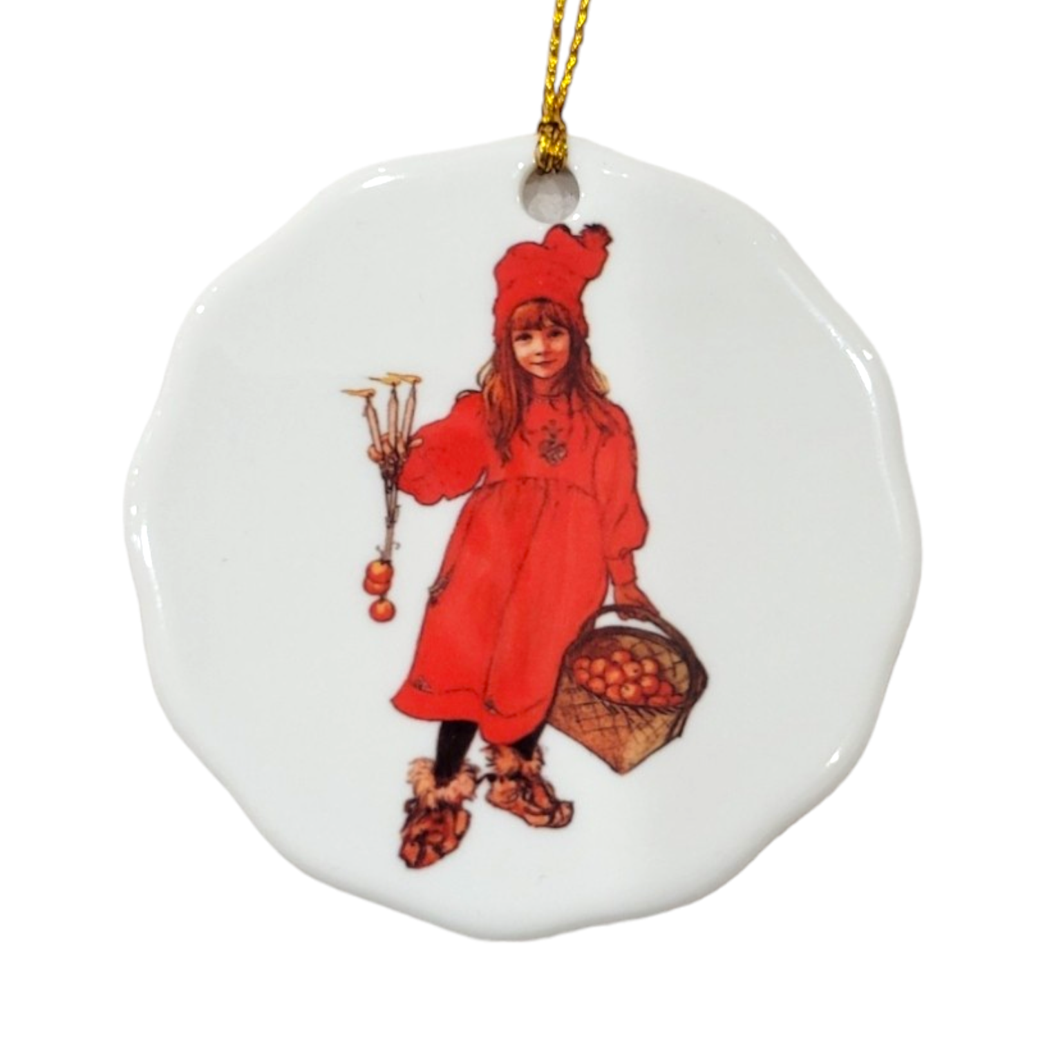 The Ornament: Apple Girl, Carl Larsson features a porcelain figure of a girl dressed in red, holding candles and a basket of apples. It comes with a gold string for hanging and brings distinctive charm to any setting.