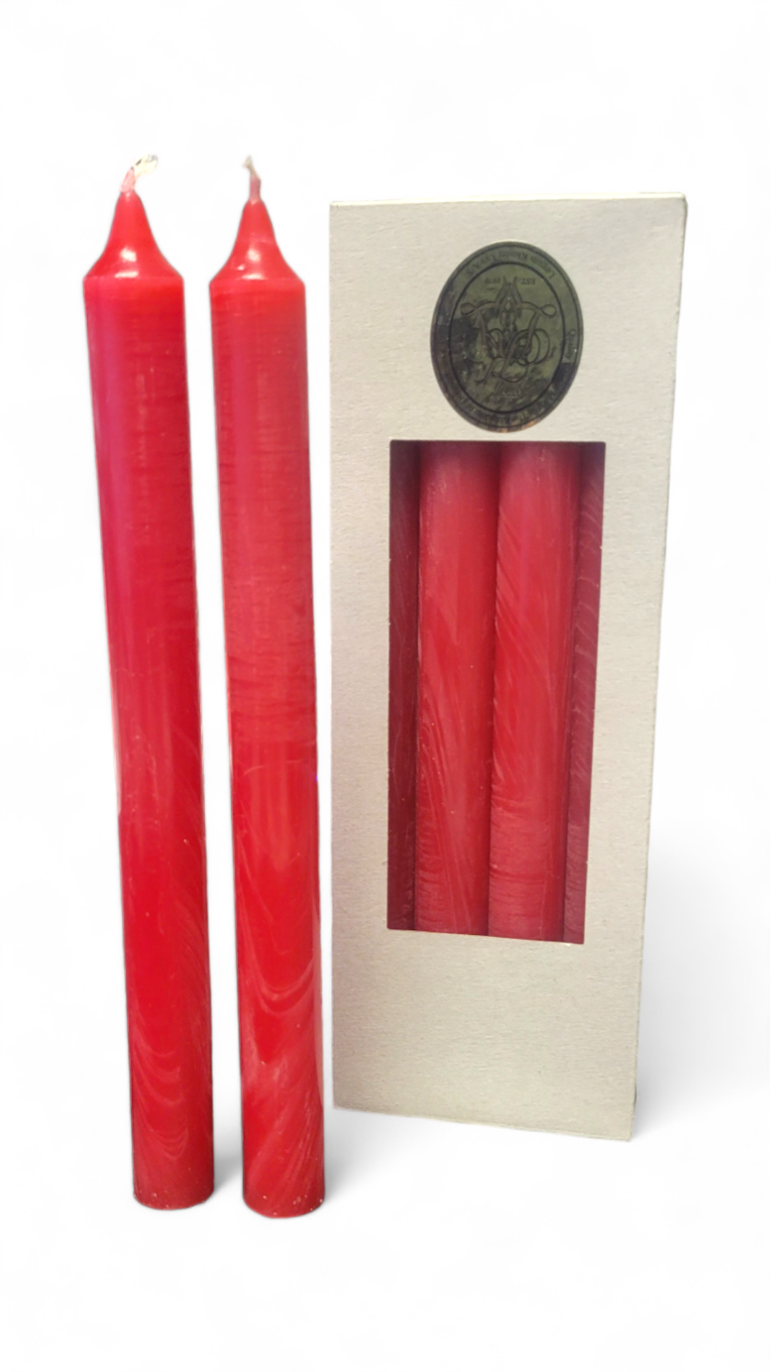 Beside the box featuring a window that reveals two identical candles, there are two Red Crown Taper Candles from the 10” Red Crown Taper 4 pack by Logum Kloster Lys A/S.