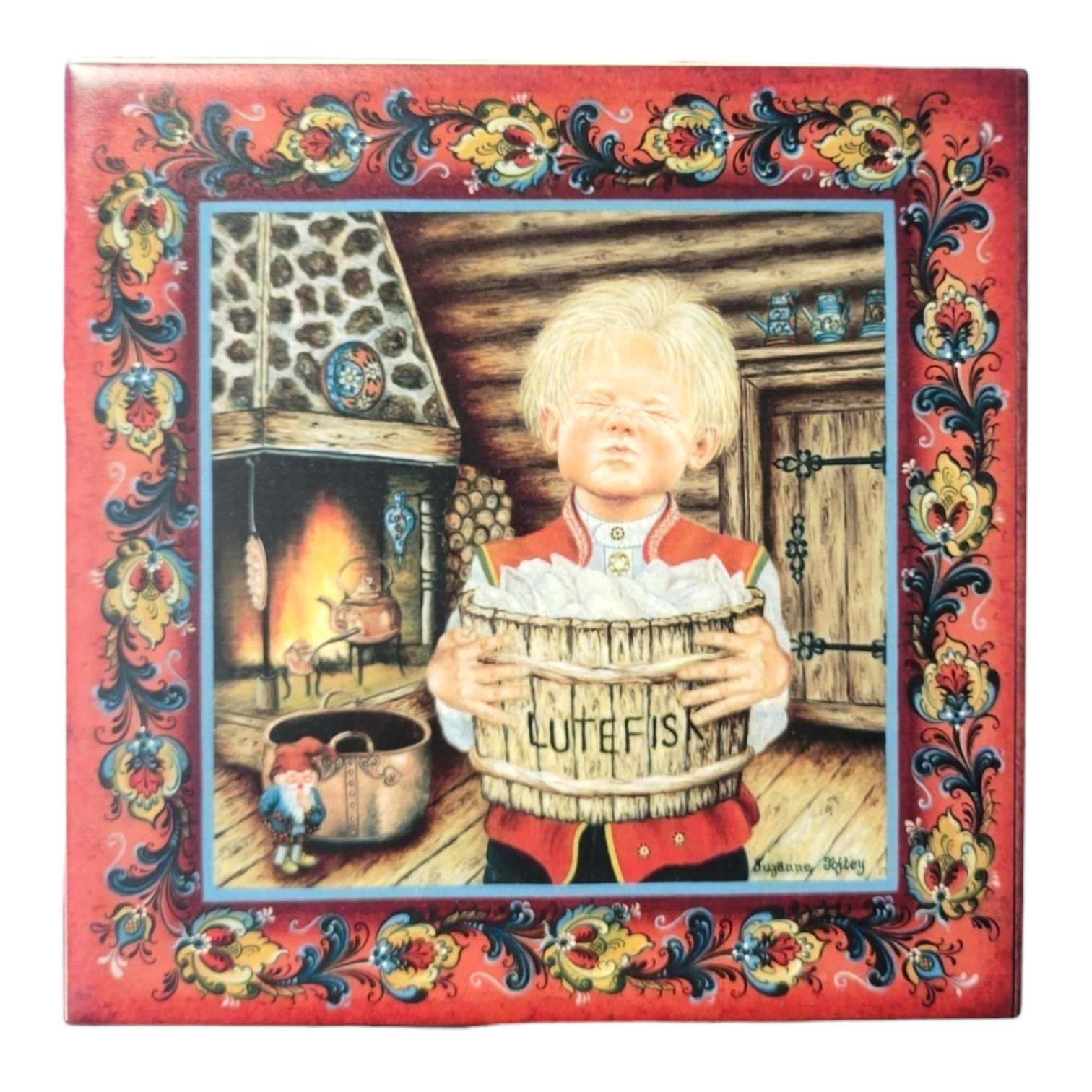 A young Lutefisk Boy stands confidently in front of a fireplace within a rustic room, holding a container marked Lutefisk. The image is elegantly enclosed with a red and floral decorative border, reminiscent of classic ceramic tile designs, featured on the "Lutefisk Boy" 6" Trivet.