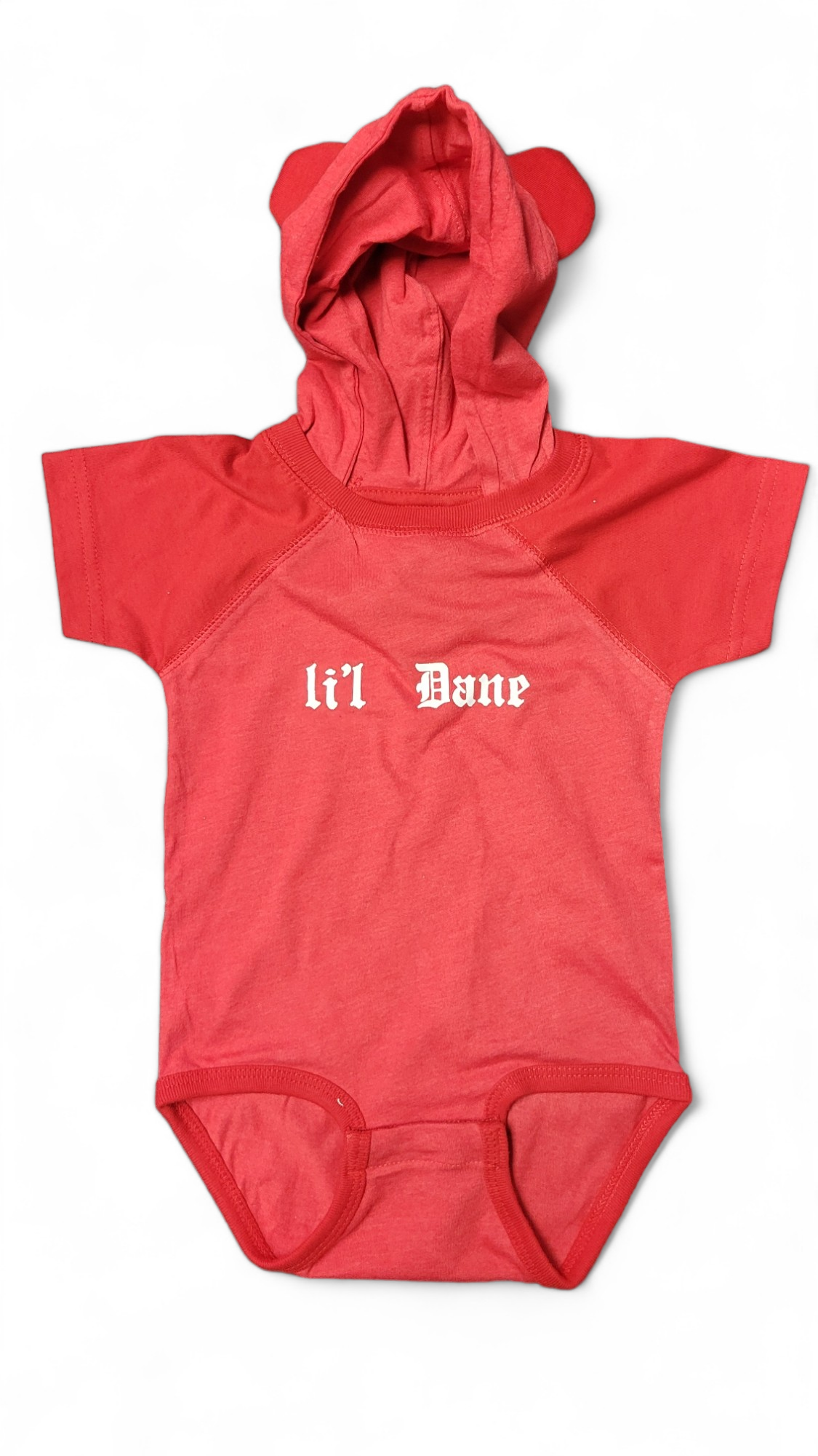 Charming "Lil Dane with Hood" red baby onesie, adorned with bear ears and showcasing the Danish flag colors. This adorable piece features the text "li'l Dane" on the front, perfect for your little one.