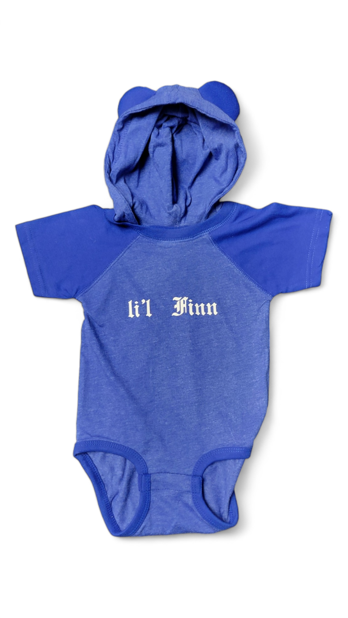 Introducing the "Onesie: Lil Fin with Hood (12mo)," a delightful blue baby onesie featuring short sleeves and an adorable hood with bear ears. Emblazoned with the "Lil Finn" text on the front, this outfit is perfect for your little one up to 12 months, subtly inspired by the colors of the Finnish flag.