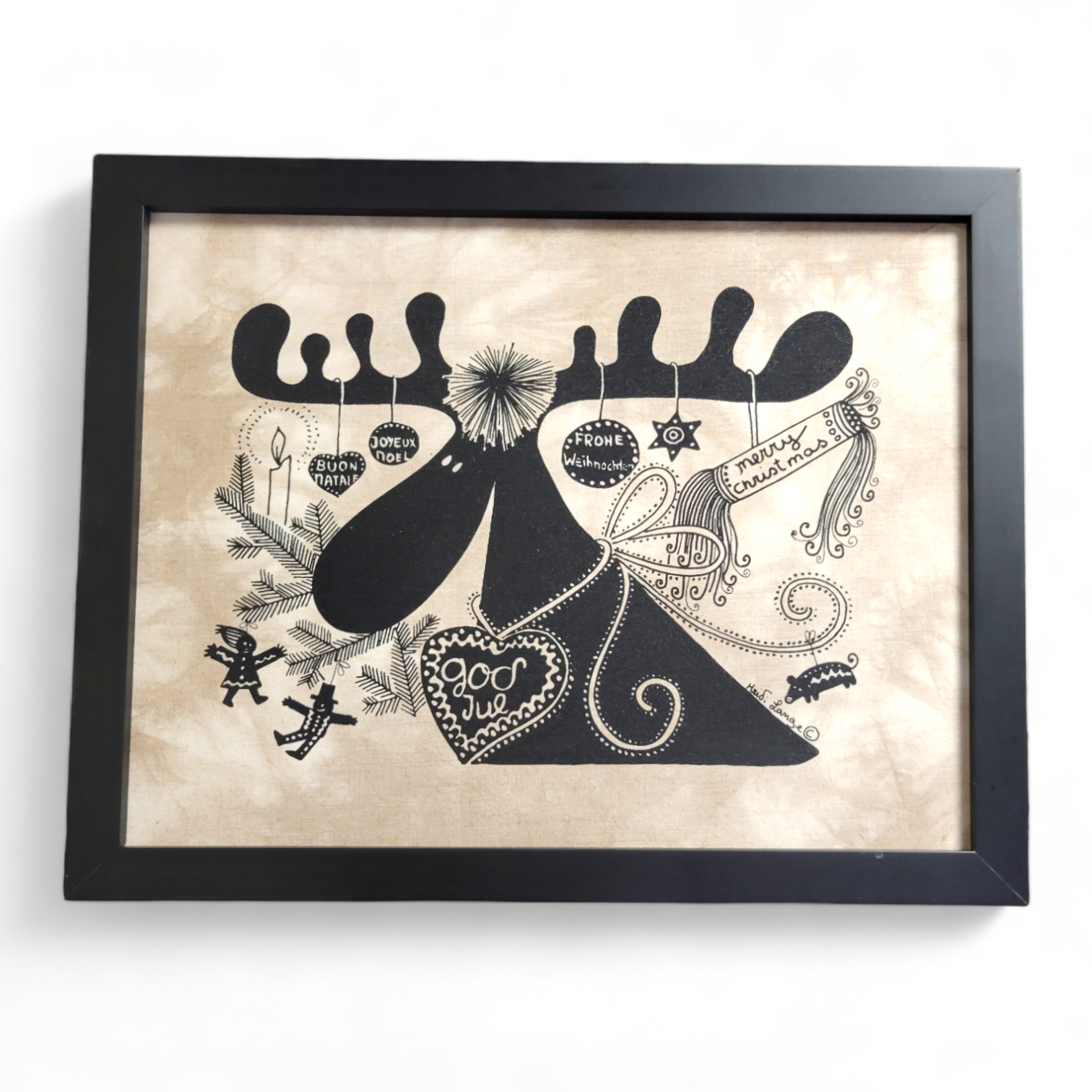 Framed artwork titled Moose God Jul by Heidi Lange features a stylized moose with ornaments, snowflakes, and decorative designs in black on a beige background, reminiscent of batik style. (14x11).