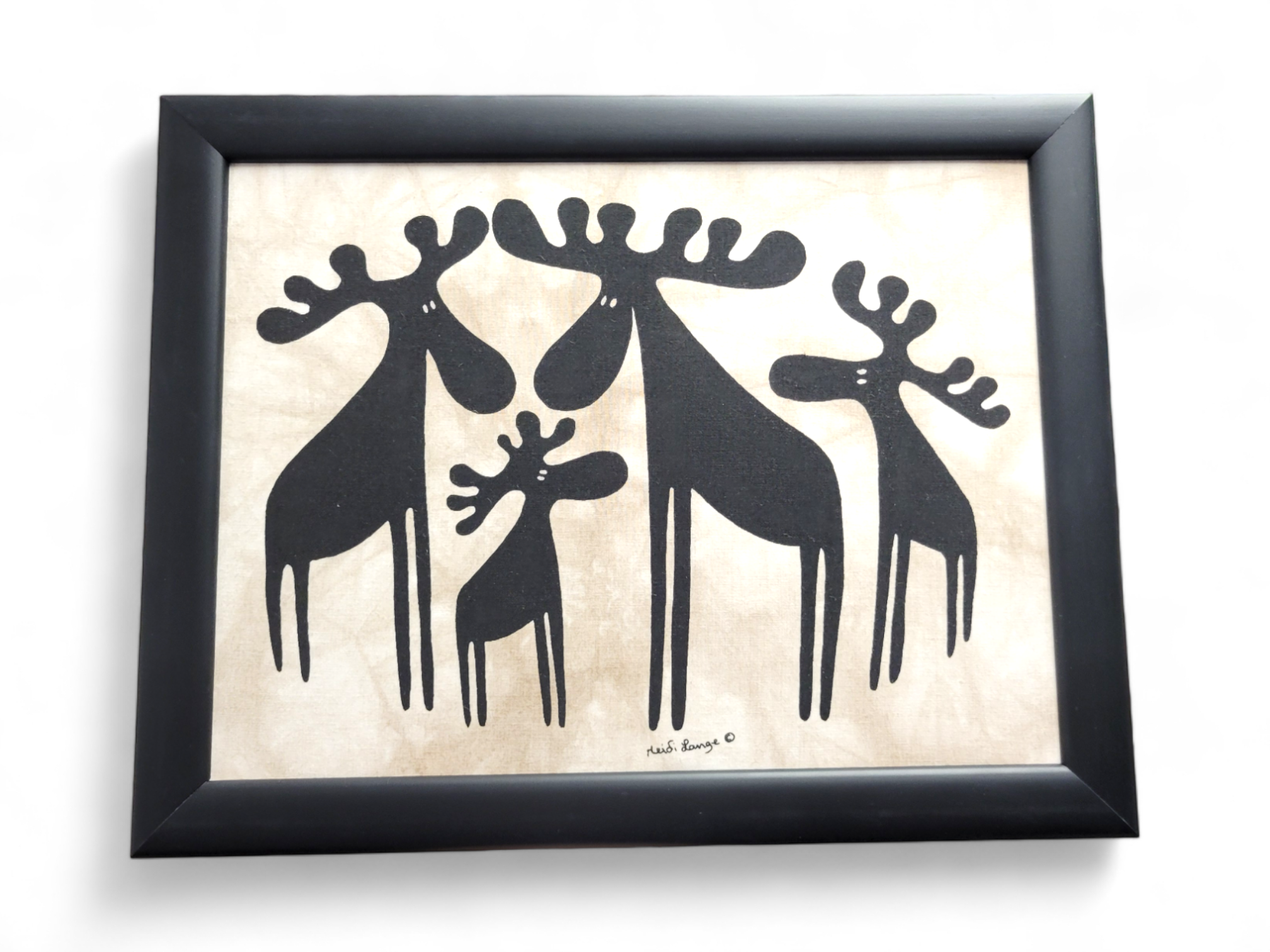 Framed artwork titled Moose Family Batik in a 13.5x10.75 black frame, featuring a stylized Moose Family of four in silhouette on a beige background.