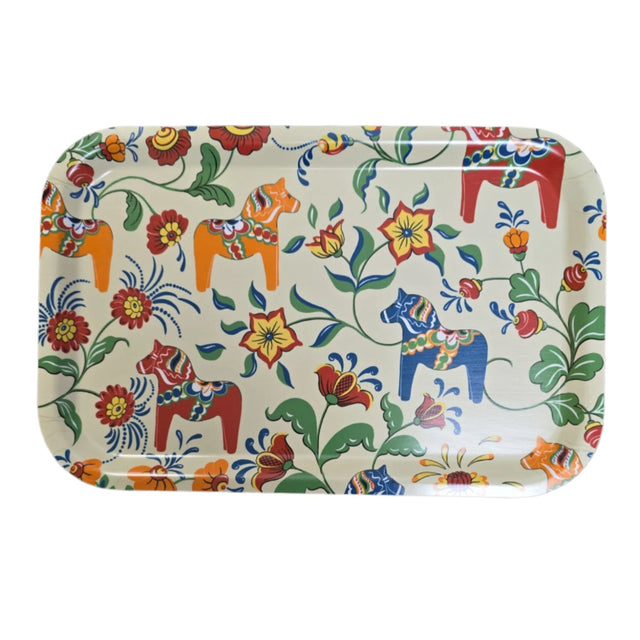 A cream-colored laminated birch tray showcases orange, red, and blue Swedish Dala Horses with a floral design on a black background.
