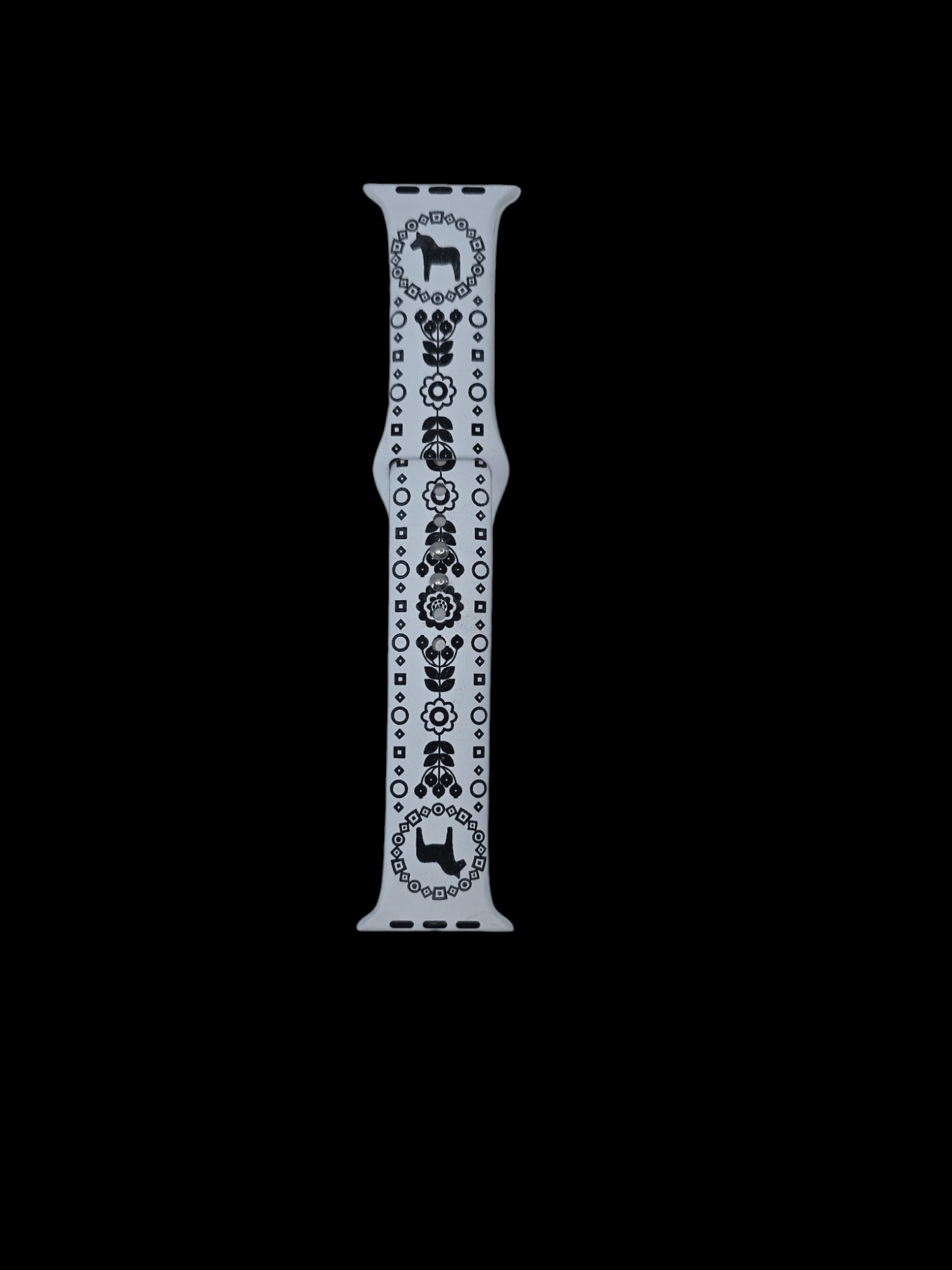 A white watch band from the Blue or White Dala Horse collection, featuring intricate black geometric designs and delicate Swedish flowers, displayed vertically against a black background.