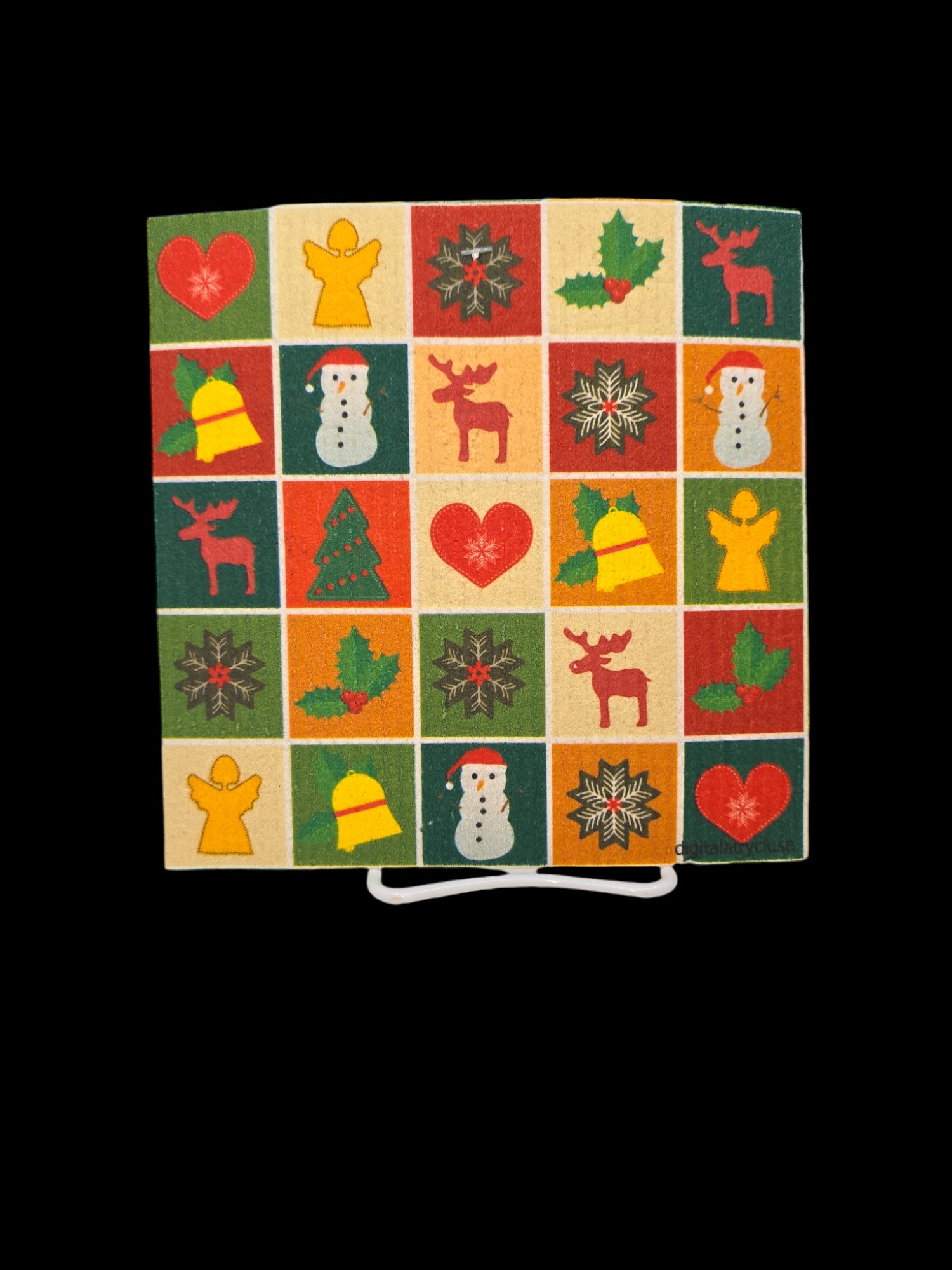 Introducing the Christmas Bingo Dish Cloth—a quilted square adorned with a grid of festive designs such as angels, hearts, and snowmen in vibrant red, green, yellow, and beige hues on a black background. This piece infuses the charm of a Swedish dishcloth into your decor with an elegant touch.