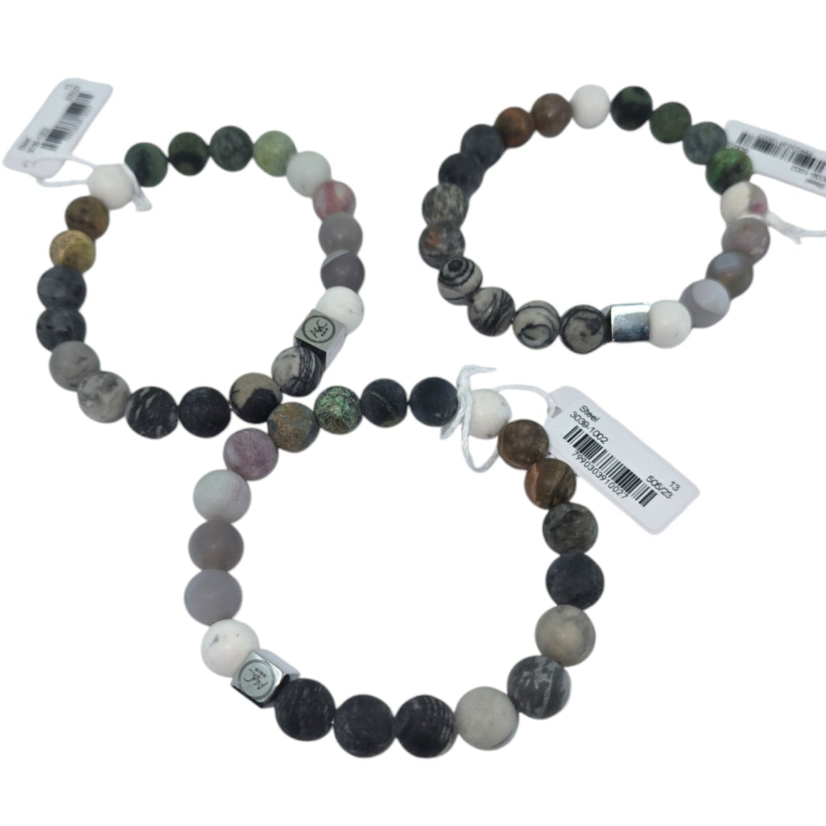 A set of three unisex bracelets, known as "Bracelet: Pure Steel Unisex Brown Tones," showcases a stretchy beaded design in Nordic-inspired shades of brown and gray, each accompanied by a tag and elegantly arranged on a white background.