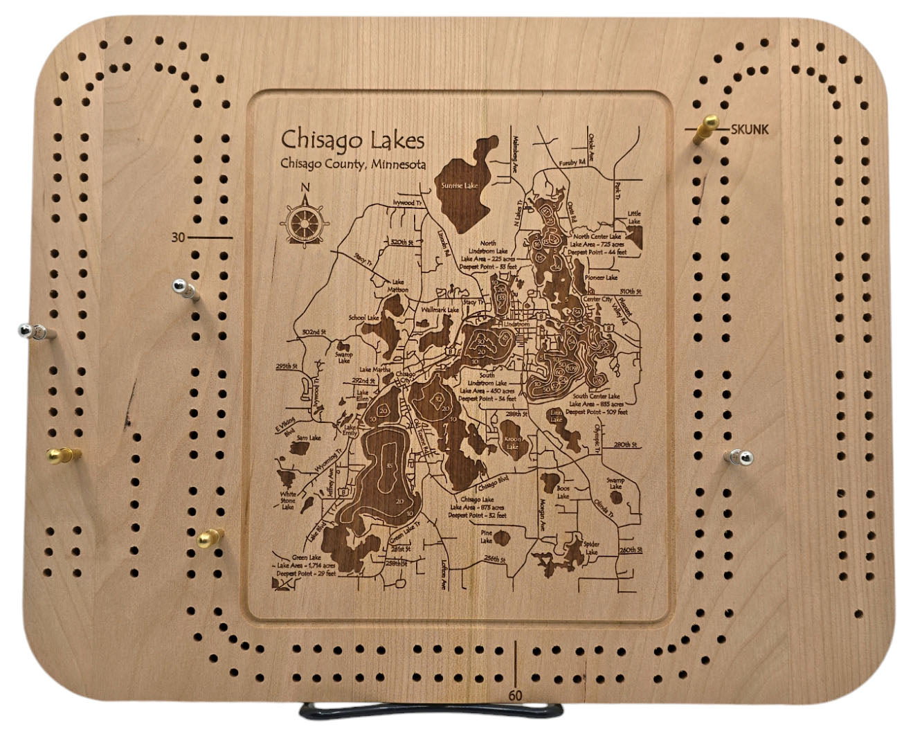 The "Game: Cribbage Board Chisago Lakes Area - Lake Map" is crafted from natural cherry and showcases an engraved map of Chisago Lakes in Chisago County, Minnesota. This regulation board includes peg holes along its edges to maintain a classic appearance.