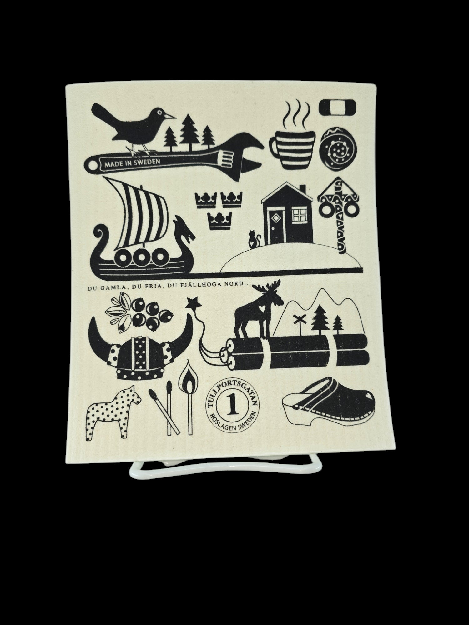 This eco-friendly dishcloth, proudly labeled "Made in Sweden," features a Swedish-themed design with illustrations of a bird, Viking ship, elk, traditional house, and trees. With Swedish text below, the stylish dishcloth is fully compostable and belongs to the collection "Dish Cloth: Made in Sweden Iconic Symbols of Sweden White with Black Print.